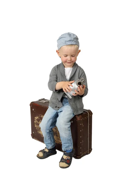 小男孩坐在老式手提箱有闹钟在手中 — 图库照片