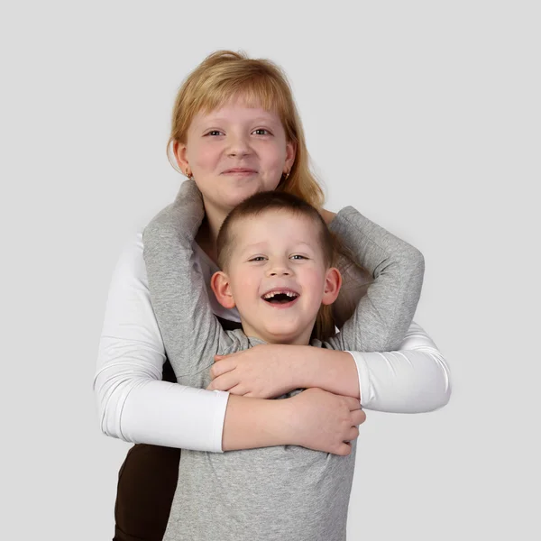 Підліток руда дівчина обіймає маленький беззубий усміхнений хлопчик — стокове фото