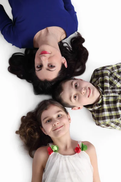 Woman, boy and girl lie on floor on gray — ストック写真