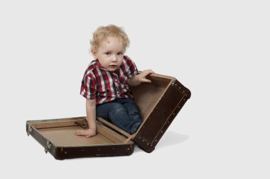 Küçük çocuk çantada oturur