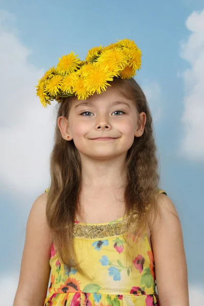 Schattig klein meisje in de krans van paardebloemen op hemelachtergrond — Stockfoto