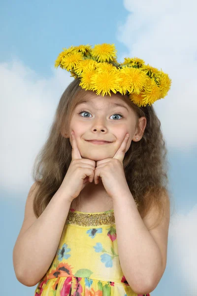 Cute little girl in wreath of dandelions on sky background — ストック写真