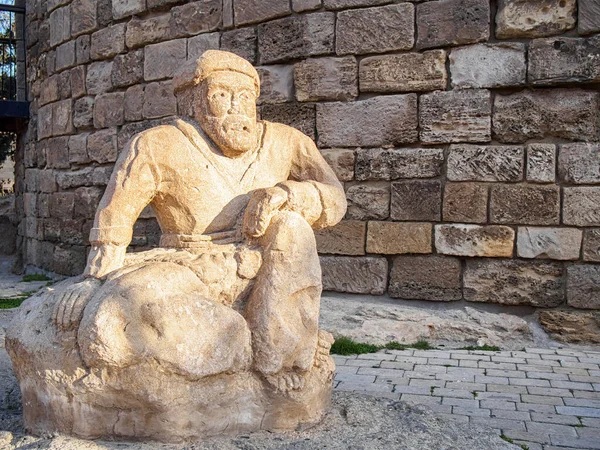 Ancient sculpture of a man at the foot of the Maiden Tower in Old Town in Baku, Azerbaijan.
