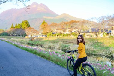 Japonya 'nın Oita şehrinde Yufuin parkında bisiklet süren genç bir kadın.