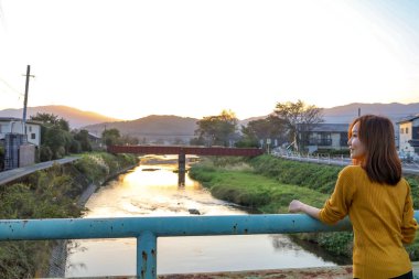 Yufuin parkında gün batımını izleyen genç bir kadın.