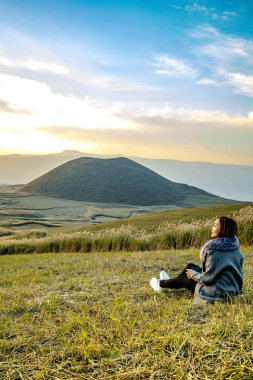 Aso Nakadake Dağı, Kumamoto, Kyushu, Japonya 'da aktif volkan arka planında oturan sevimli Japon kız.)