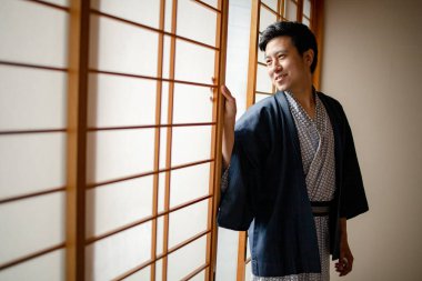 Lovely Asian man wearing Yukata japanese tradditional cloth in traddition Japan style in Tatami room. Face on happy time in Japan with copy space.