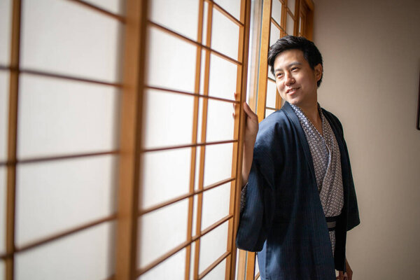 Lovely Asian man wearing Yukata japanese tradditional cloth in traddition Japan style in Tatami room. Face on happy time in Japan with copy space.