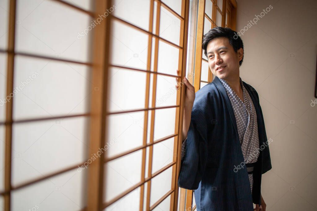 Lovely Asian man wearing Yukata japanese tradditional cloth in traddition Japan style in Tatami room. Face on happy time in Japan with copy space.