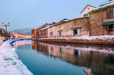 Otaru, Hokkaido, Japonya - Aralık 2019: Otaru Kanalı kışın alacakaranlık ışıklarıyla. Otaru Kanalı 'nda eski depoları olan güzel bir sahne. Japonya 'nın Hokkaido kentinde popüler bir turistik merkezdir..