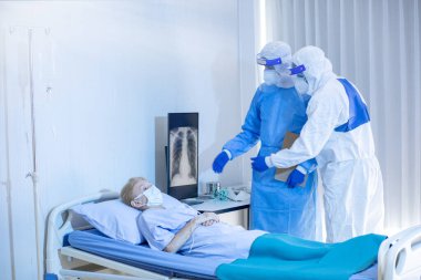 Hastane karantina odasındaki yatakta yatarken enfeksiyon kapmış 19 hastaya doktor ve hemşire bakıyor. Coronavirus covid 19 hastalığı. Corona virüsü dünya çapında sosyal bir sorundur.
