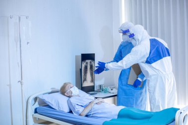 Hastane karantina odasındaki yatakta yatarken enfeksiyon kapmış 19 hastaya doktor ve hemşire bakıyor. Coronavirus covid 19 hastalığı. Corona virüsü dünya çapında sosyal bir sorundur.