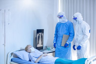 Hastane karantina odasındaki yatakta yatarken enfeksiyon kapmış 19 hastaya doktor ve hemşire bakıyor. Coronavirus covid 19 hastalığı. Corona virüsü dünya çapında sosyal bir sorundur.