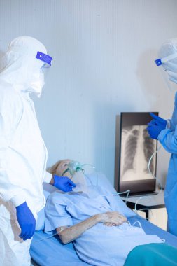 Hastane karantina odasındaki yatakta yatarken enfeksiyon kapmış 19 hastaya doktor ve hemşire bakıyor. Coronavirus covid 19 hastalığı. Corona virüsü dünya çapında sosyal bir sorundur.
