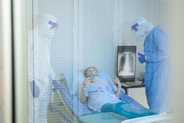 Hastane karantina odasındaki yatakta yatarken enfeksiyon kapmış 19 hastaya doktor ve hemşire bakıyor. Coronavirus covid 19 hastalığı. Corona virüsü dünya çapında sosyal bir sorundur.