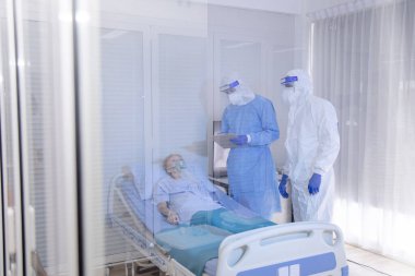 Hastane karantina odasındaki yatakta yatarken enfeksiyon kapmış 19 hastaya doktor ve hemşire bakıyor. Coronavirus covid 19 hastalığı. Corona virüsü dünya çapında sosyal bir sorundur.