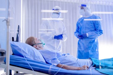 Hastane karantina odasındaki yatakta yatarken enfeksiyon kapmış 19 hastaya doktor ve hemşire bakıyor. Coronavirus covid 19 hastalığı. Corona virüsü dünya çapında sosyal bir sorundur.