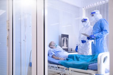 Doktor ve hemşire Covid19 hastasıyla ilgileniyorlar. Hastalıklı kovid19 hastasında umutsuzca bir ruh hali var. Hastanenin karantina odasında yatarken..