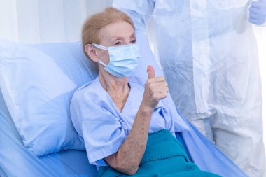 Yaşlı kadın hasta, Coronavirus veya COVID19 'dan sonra sağlık ekibinin geçmişine sahip tekerlekli sandalyede küçük bir kalp taşıyor. Başarı kavramı aşıyı ve takım çalışmasını keşfetti.