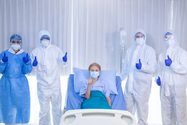 Yaşlı kadın hasta, Coronavirus veya COVID19 'dan sonra sağlık ekibinin geçmişine sahip tekerlekli sandalyede küçük bir kalp taşıyor. Başarı kavramı aşıyı ve takım çalışmasını keşfetti.