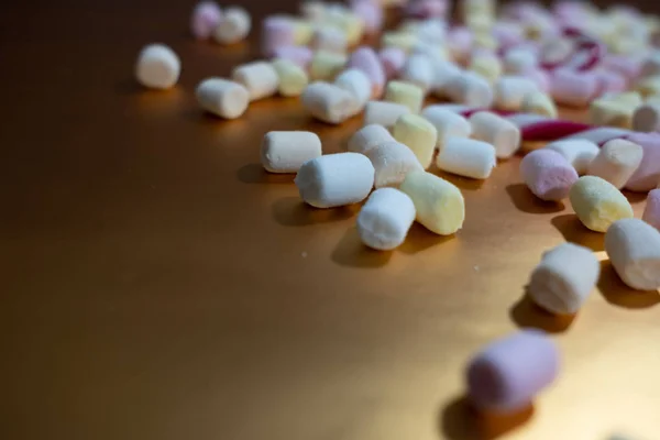 Viele winzige und bunte Marshmallows auf einer glänzenden Goldoberfläche — Stockfoto