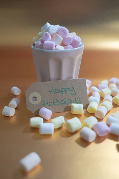 Frohe Feiertage Handschrift und eine Tasse voll Marshmallows auf einem b — Stockfoto