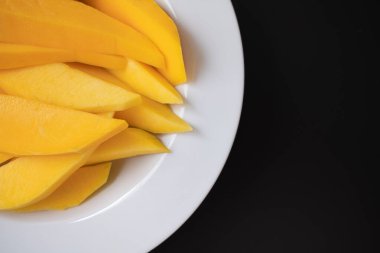 Mango, arka planda beyaz bir tabağı keser.