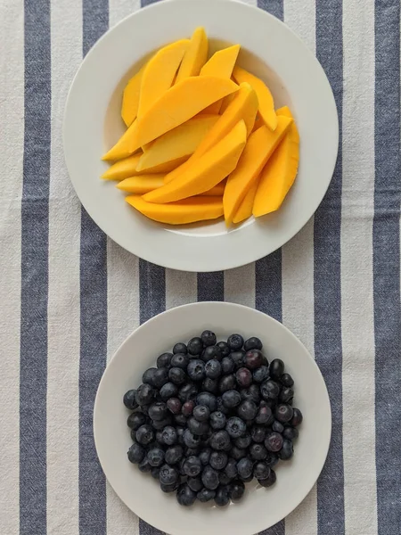 Potongan Mangga Dan Blueberry Pada Taplak Meja Biru Dan Putih Stok Gambar
