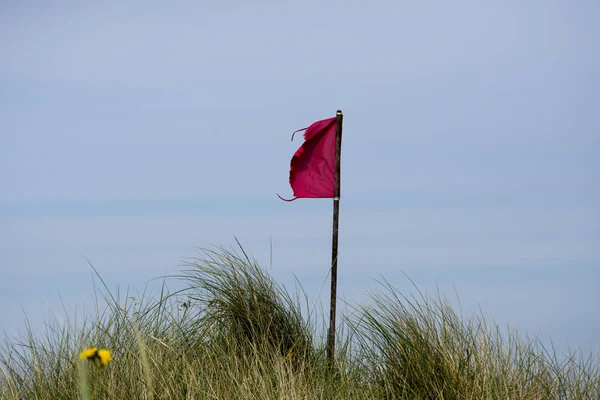 Červená vlajka a pobřeží — Stock fotografie