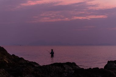 Gün batımının altında insan siluetleriyle güzel bir deniz manzarası