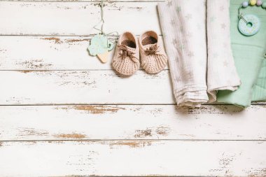 Yeni doğan bebek kundaklama giysileri, çizmeler ve bağlar beyaz tahta arka planda fotokopi alanı ile. Bebek moda konsepti.