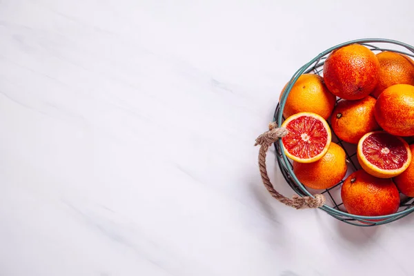 Oranges sanguines siciliennes tranchées dans un panier en métal sur un fond de marbre naturel . — Photo