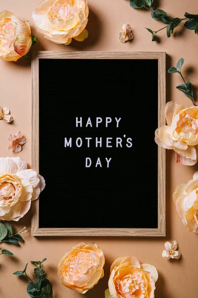 Roses and letter board on a beige background. Mother's day. Flat lay, top view.