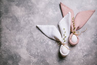 Mutlu Paskalyalar. Paskalya tavşanı. Gri arka planda tomurcukları olan Paskalya yumurtaları ve dalları. Düz konum, üst görünüm, kopyalama alanı.