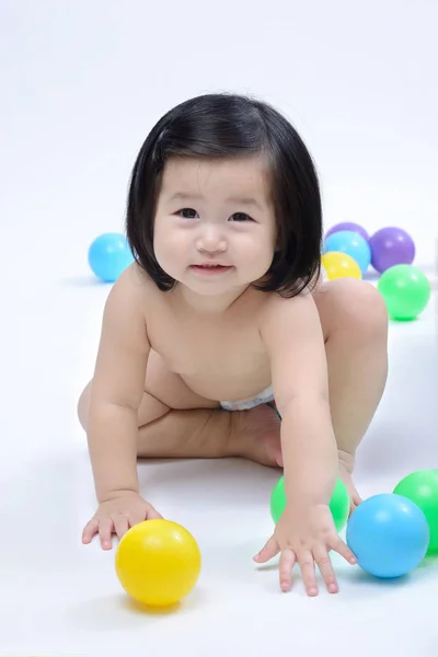 Asiático bebé chica sonriendo y arrastrándose es jugando con colorido ba —  Fotos de Stock