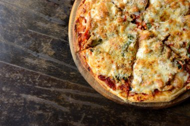 Sıcak pizza dilimi, erimiş peynirle kırsal ahşap bir masada..