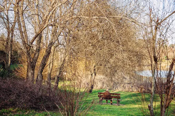 Az ember egyedül ül egy padon a parkban — Stock Fotó