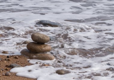 Okyanusun kenarında yığılmış üç küçük taş