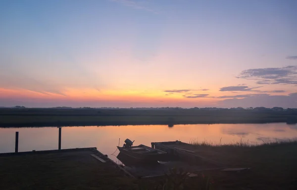 Ön planda küçük bir tekne ile kıyı bir kanal üzerinden günbatımı demirledi