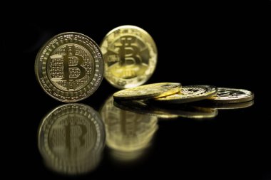 Bitcoin sikke yansıtıcı yüzeyi siyah bir zemin üzerine koyulur ve kenarlarına monte edilir.