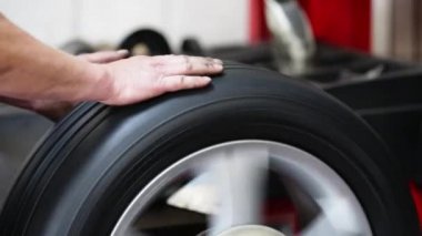 Otomobil tamircisi dengeleme makinesinde otomatik lastiği denetliyor