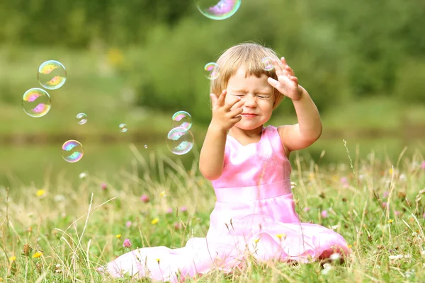 Boldog kis lány kergeti a buborékok — Stock Fotó