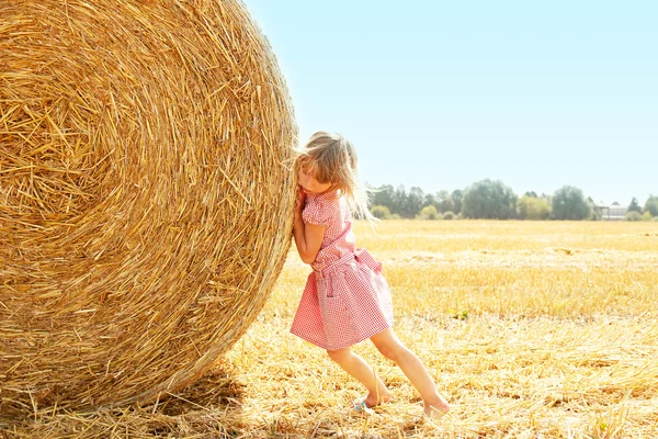 Happy child on a field with bales harvest — Stock Photo, Image