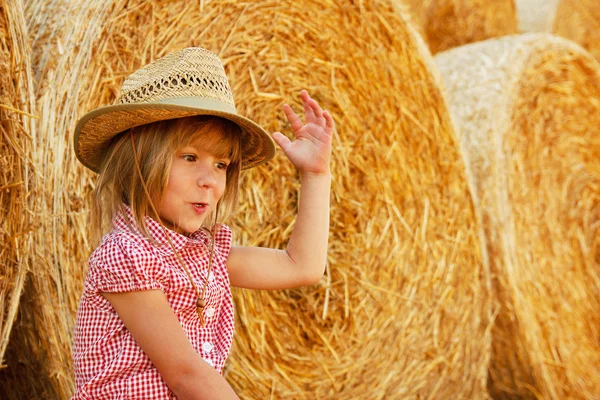 Happy child on a field with bales harvest — Stock Photo, Image