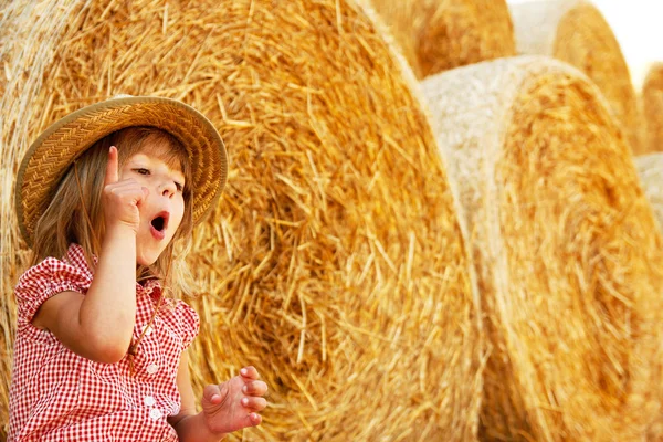 Šťastné dítě na poli s balíky sklizeň — Stock fotografie