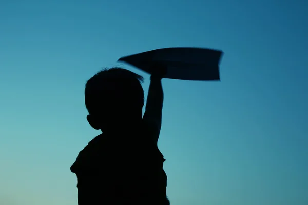 Детский силуэт держит картонный самолет — стоковое фото