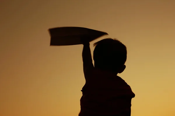 Детский силуэт держит картонный самолет — стоковое фото