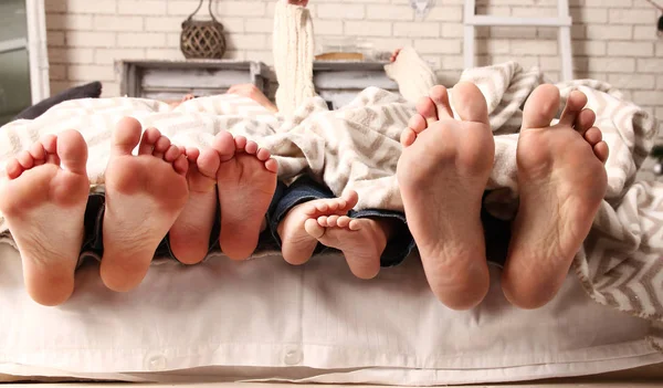 Füße der Familie stochern unter Decke hervor — Stockfoto
