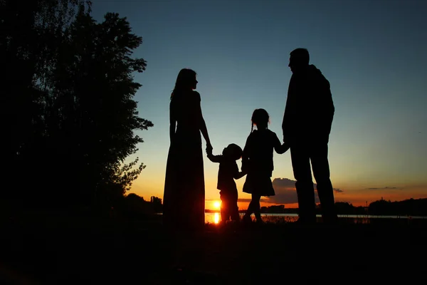 Silhouette einer glücklichen Familie beim Händchenhalten — Stockfoto