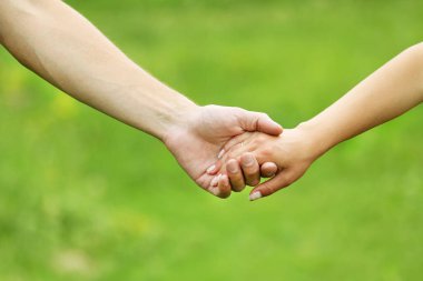 Mutlu aile ve çocuk parkta el ele tutuşuyor.